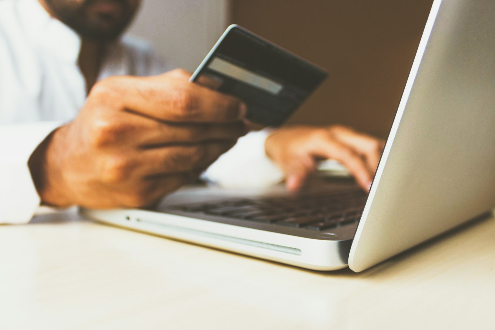 A person holding a plain bank card at a laptop while their applications are filled in and submitted for them.
